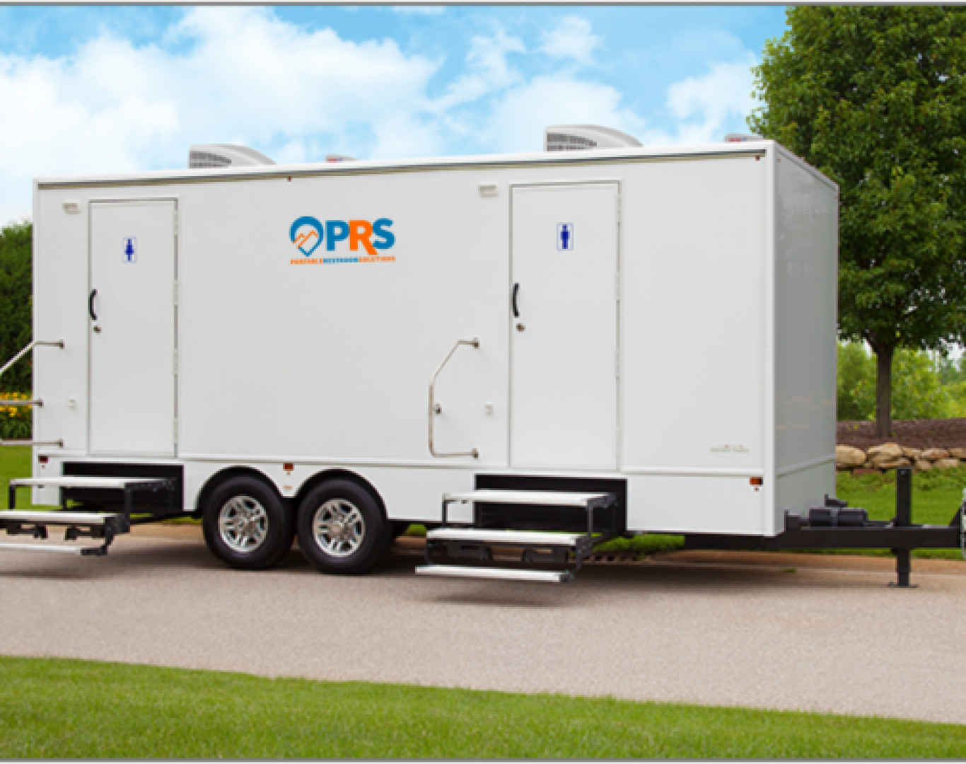 Team setting up for a wedding with Restroom trailer rental in Boulder, CO beside a tented reception